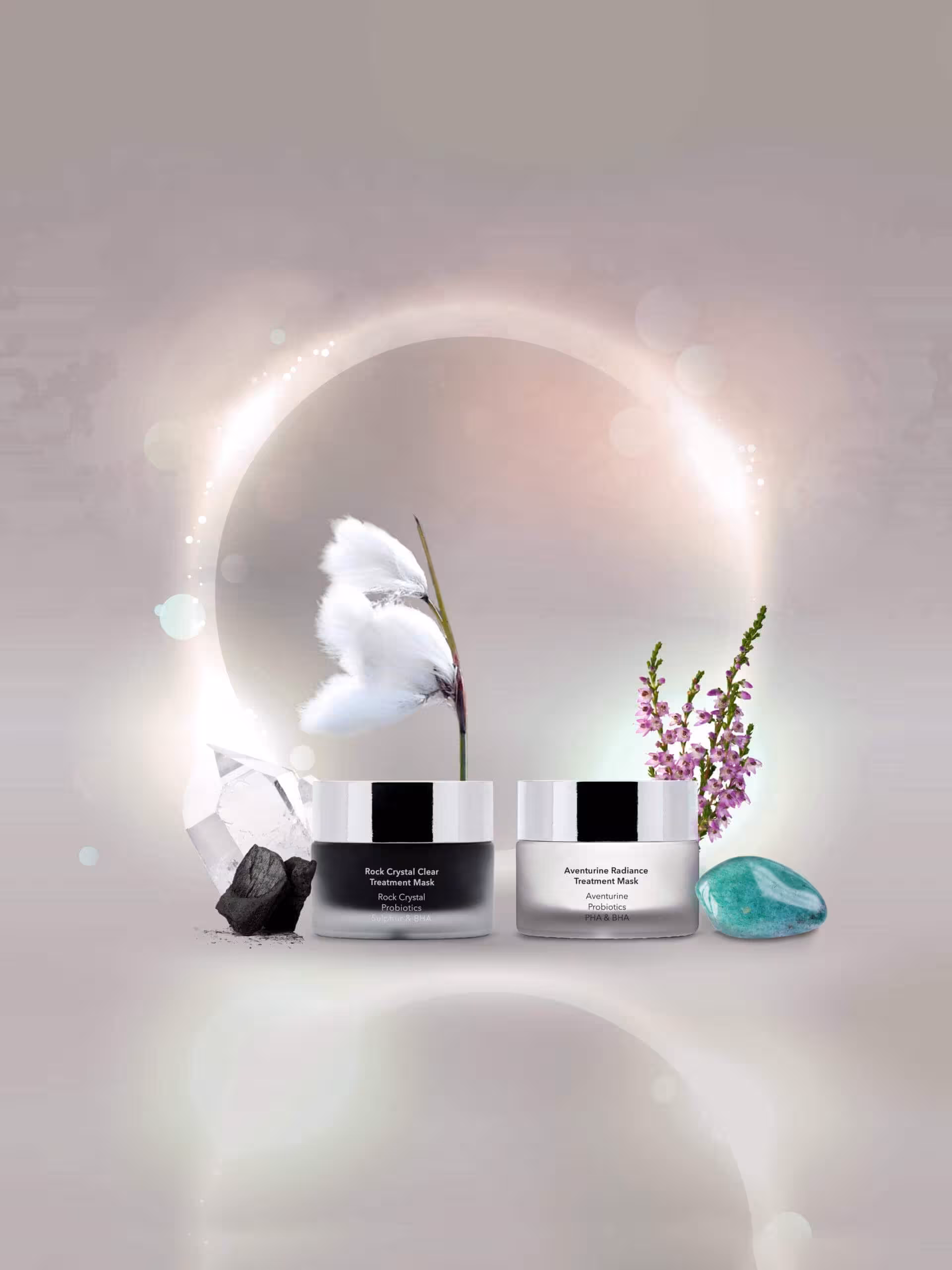 Produktbild av ansiktsmask och peeling Rock Crystal Clear Treatment Mask och Aventurine Radiance Treatment Mask från M Picaut Skincare. Glasburkar med svart och vit mask, omgivna av blänkande gloria och ingredienser kol, bergskristall, ängsull, ljung och aventurine.